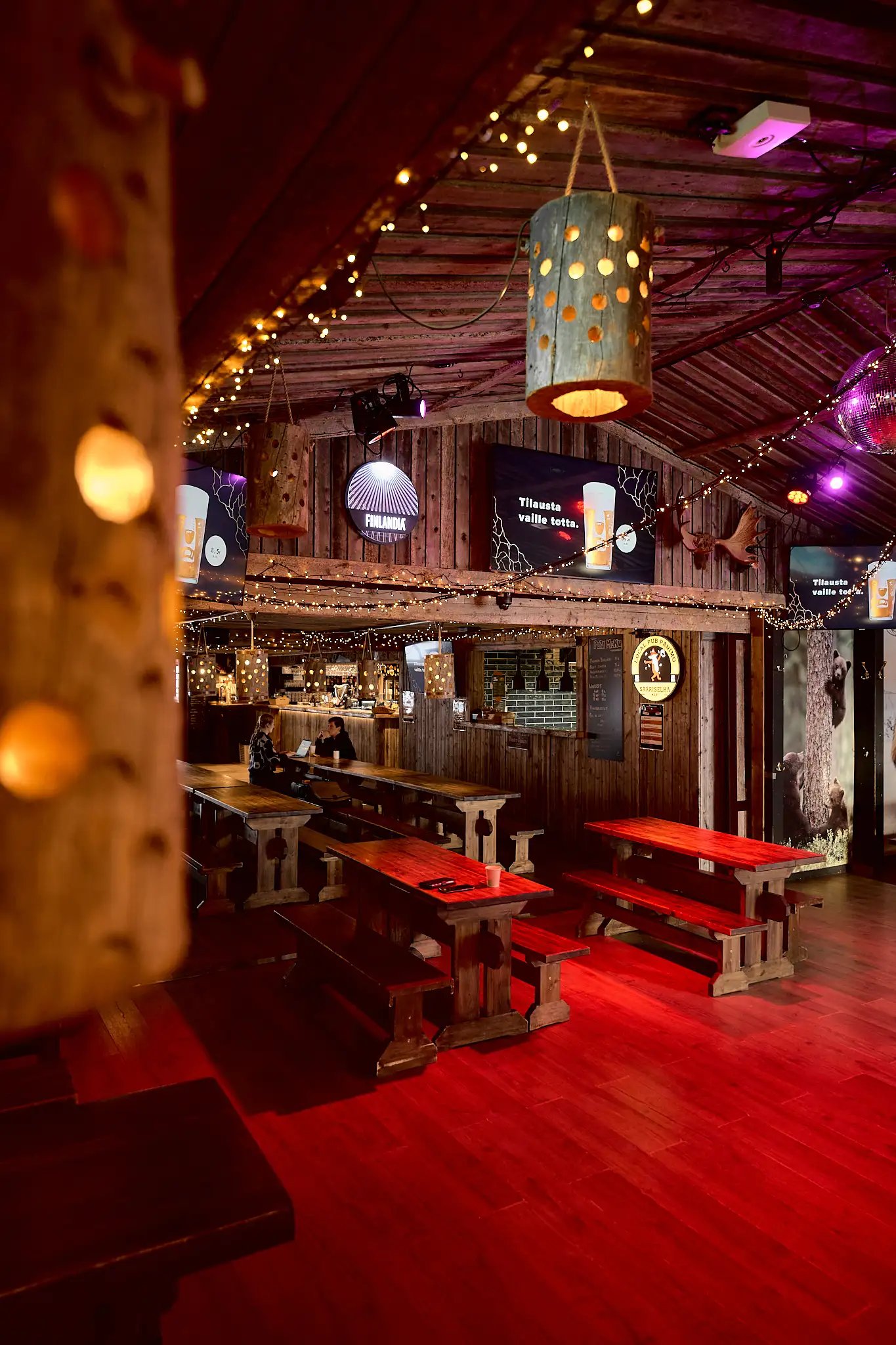 Restaurant interior. Long wooden tables and chairs in red lighting.