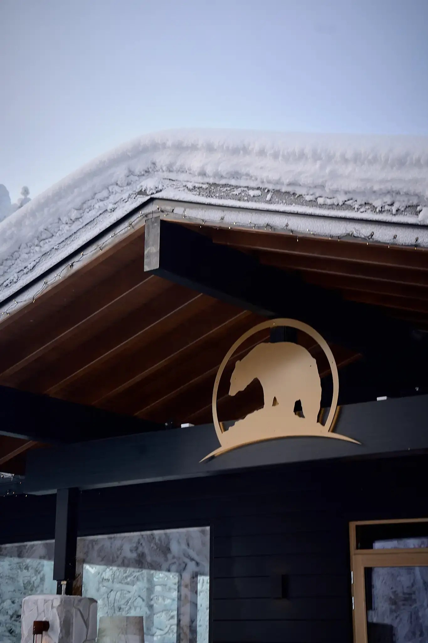 Hirsirakennus ja luminen katto. Seinällä Wilderness Hotelsien logo.