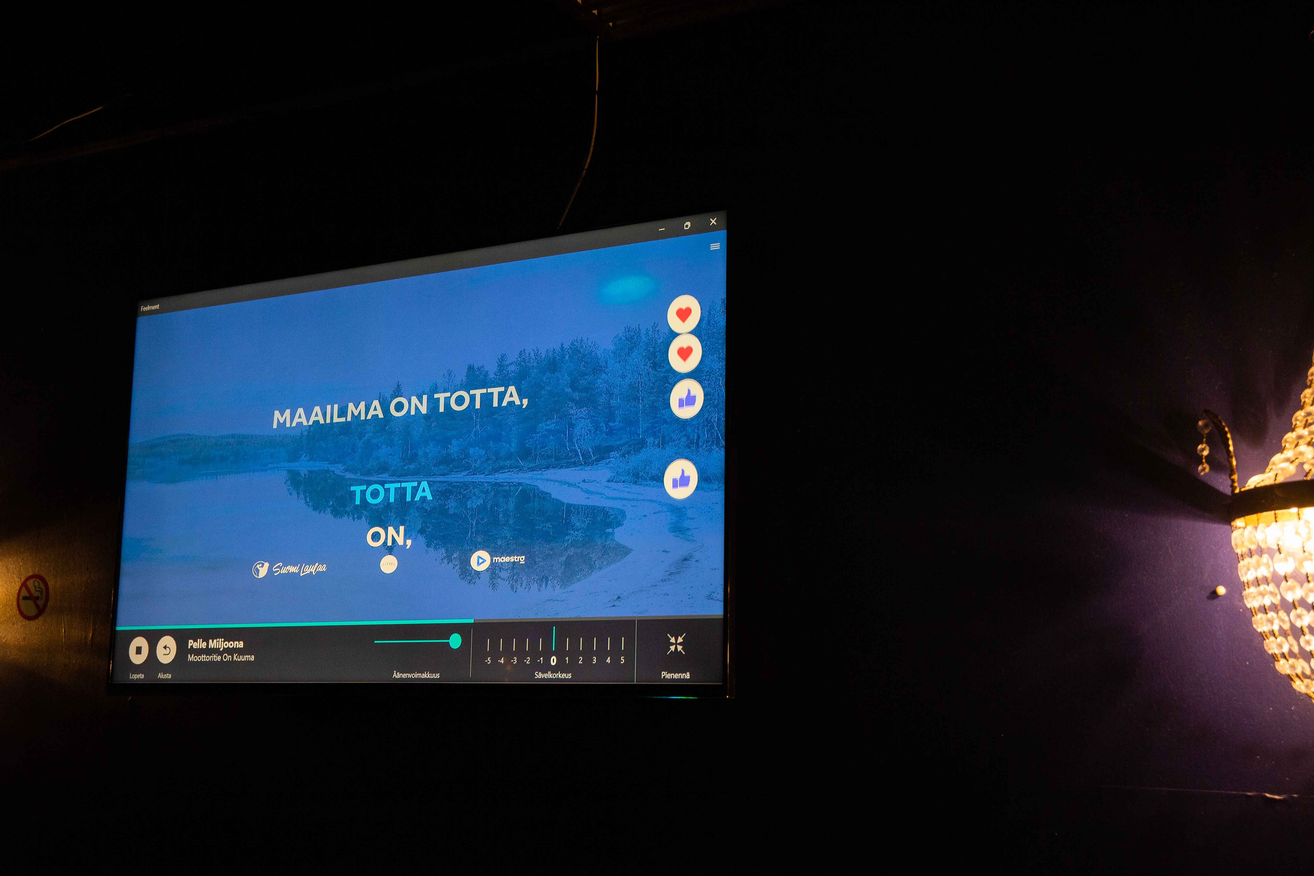 Seinällä oleva tv-ruutu, jossa pyörii karaokekappale.
