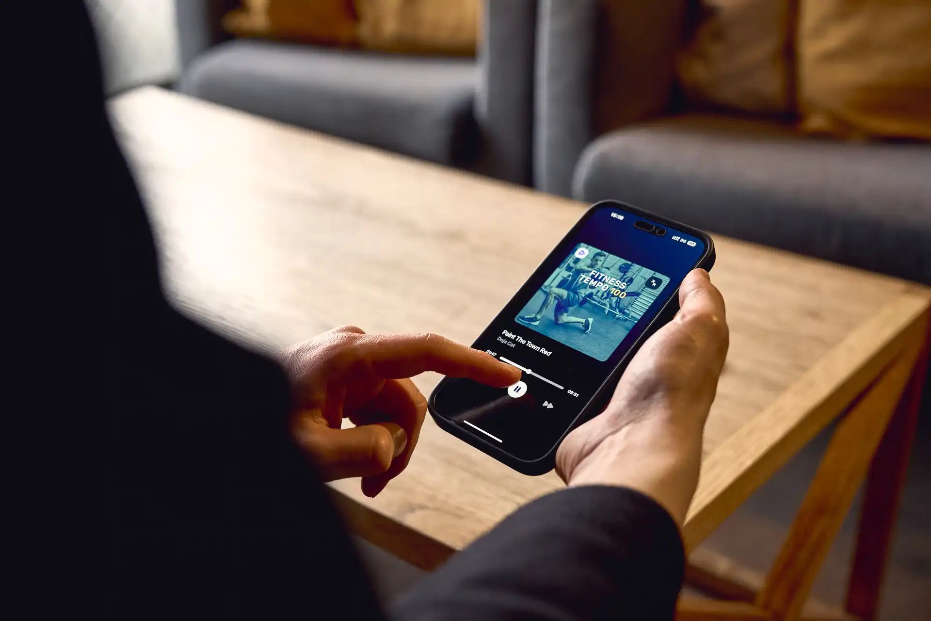 Henkilö klikkaamassa puhelimen näytöllä näkyvää play-nappulaa.