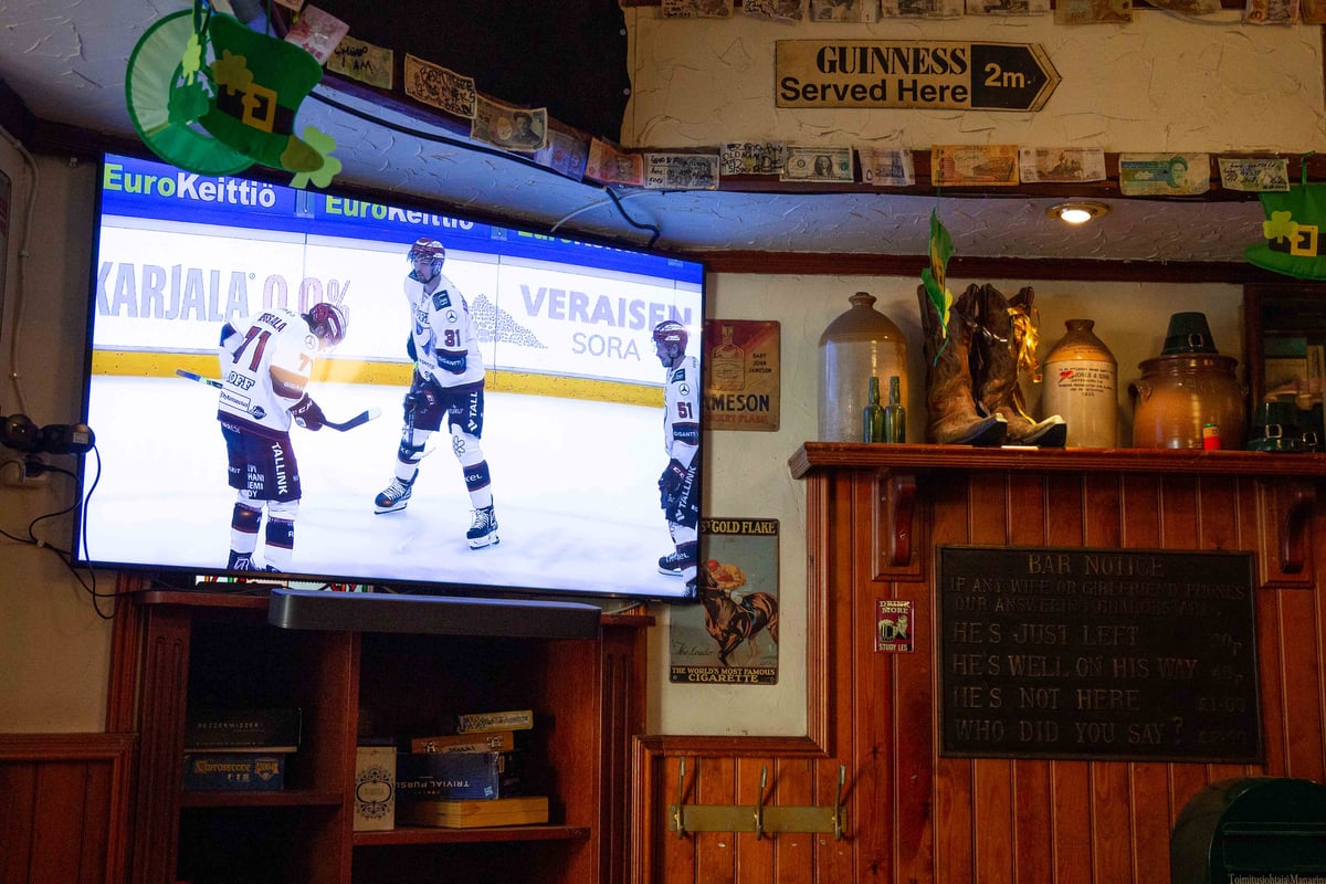 Tv-ruutu, jossa pyörii jääkiekko-ottelu. Irish Pub -tunnelmaa.
