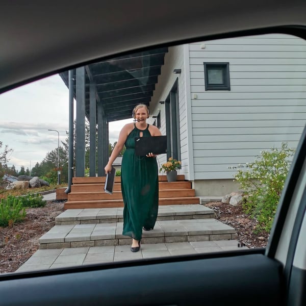 Juulianna, an employee of Feelment, assisting a customer remotely. She's holding a computer, wearing headphones, and dressed in formal attire.