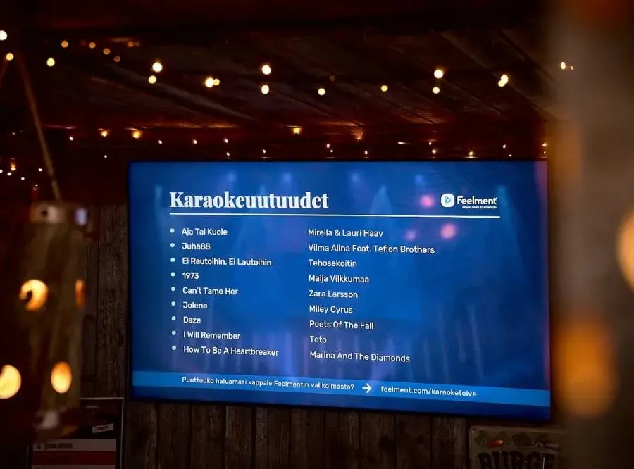 Ravintolan seinällä oleva tv-ruutu, jossa näkyy karaokeuutuuksia.
