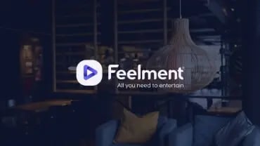 Feelmentin valkoinen logo. Taustalla ravintolan sisätilat.