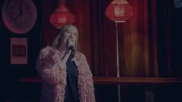 Nainen laulamassa karaokea hämyisessä ravintolassa.