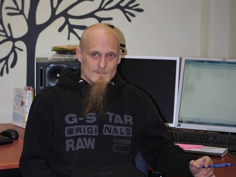 A bald, young man sitting at his work desk. 