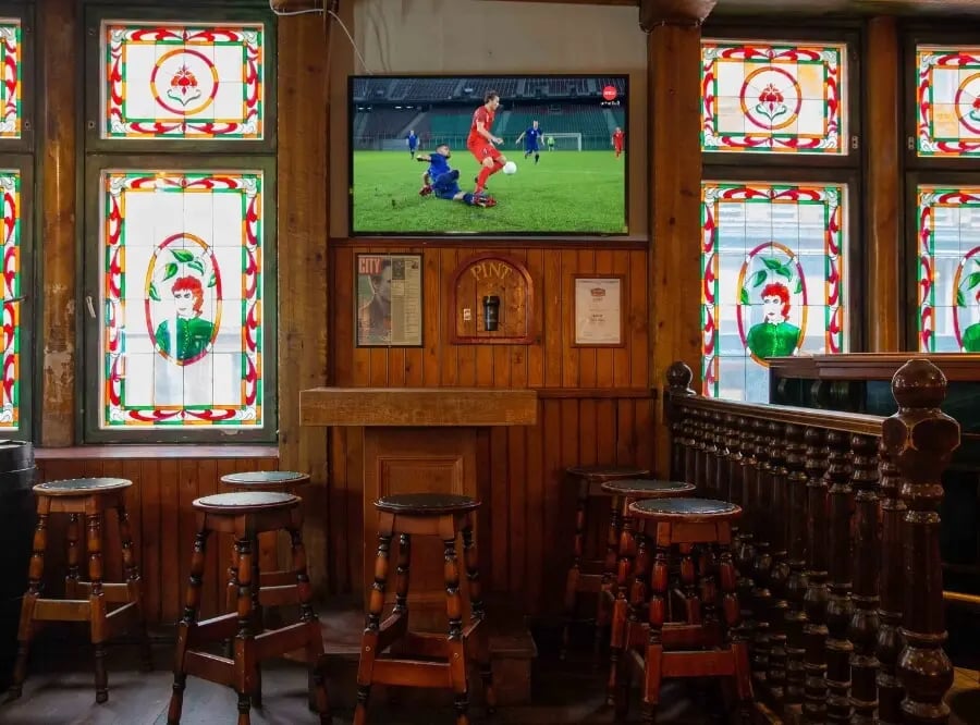 Ravintolan seinällä oleva televisioruutu, jossa näkyy jalkapallo-ottelu.