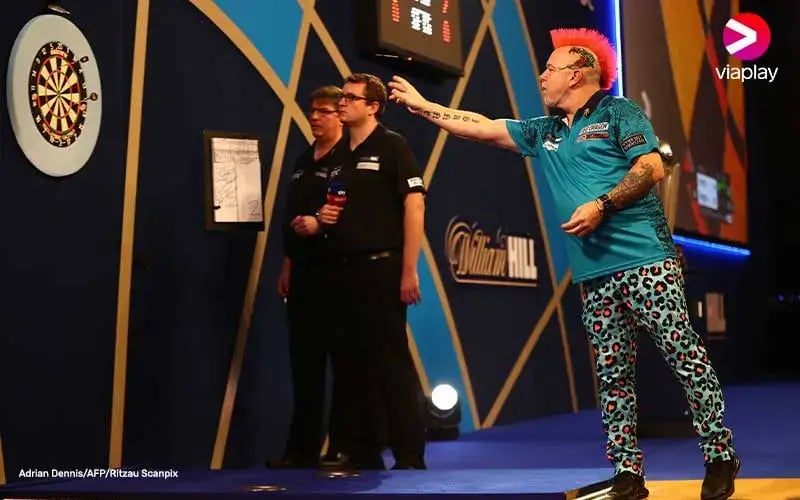 Man throwing a dart with two judges in the background.