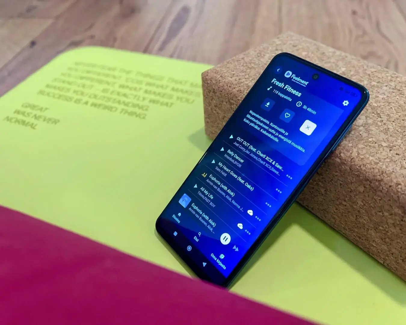 A phone with a green yoga mat, showing the Feelment app.