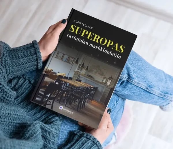 Nainen istumassa sylissään kirja, jonka kannessa teksti