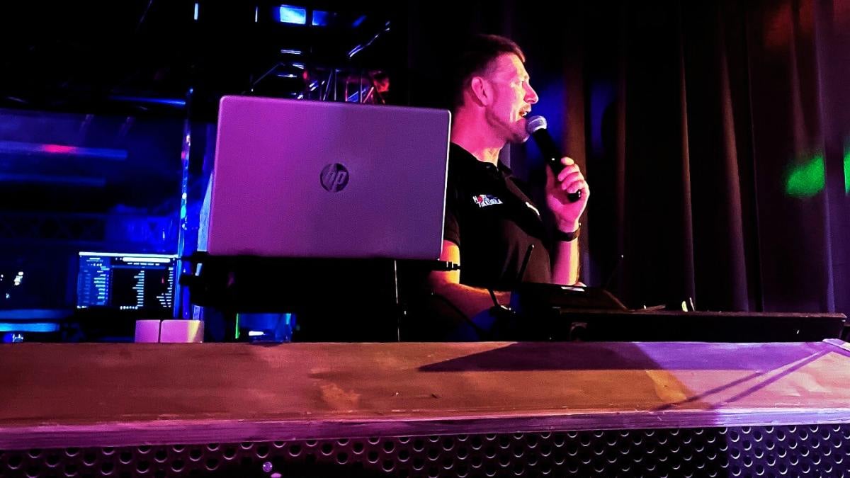 A male host conducting karaoke behind the counter.