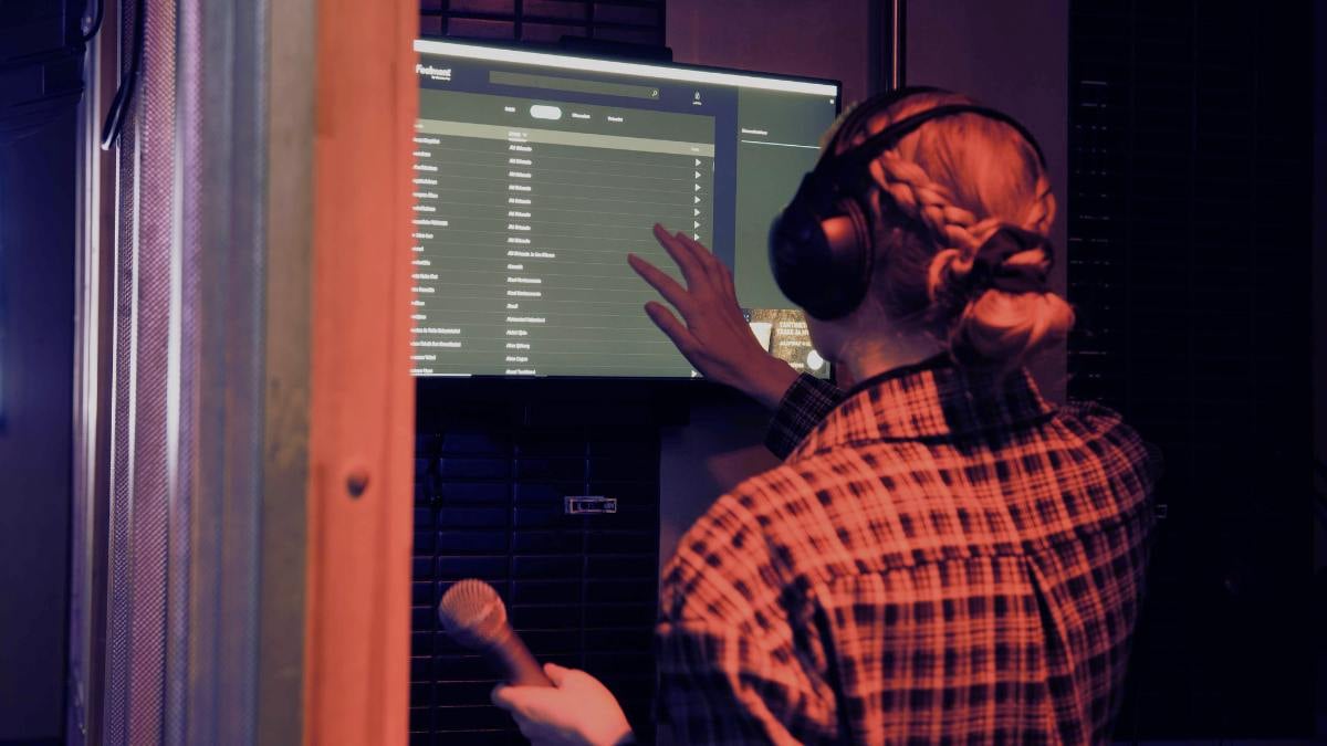 A restaurant customer selecting a karaoke song from a touchscreen while holding a microphone.