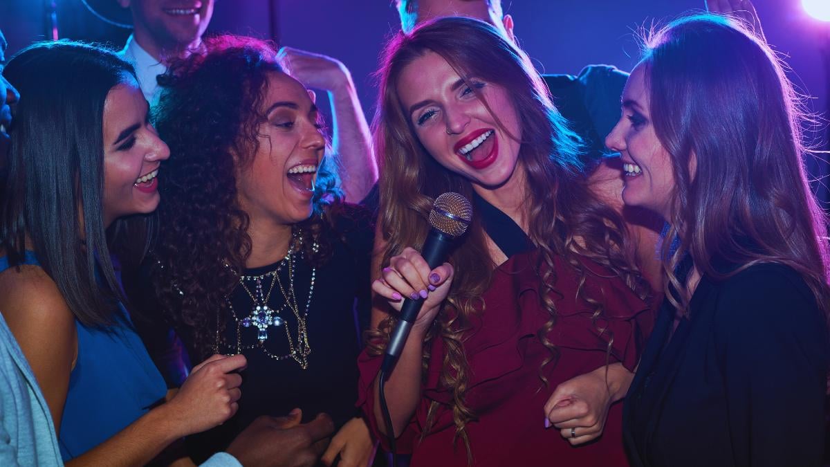 A group of happy restaurant customers singing together into a microphone.