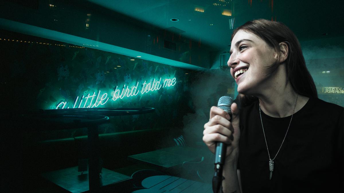 A smiling woman holding a microphone in a restaurant.