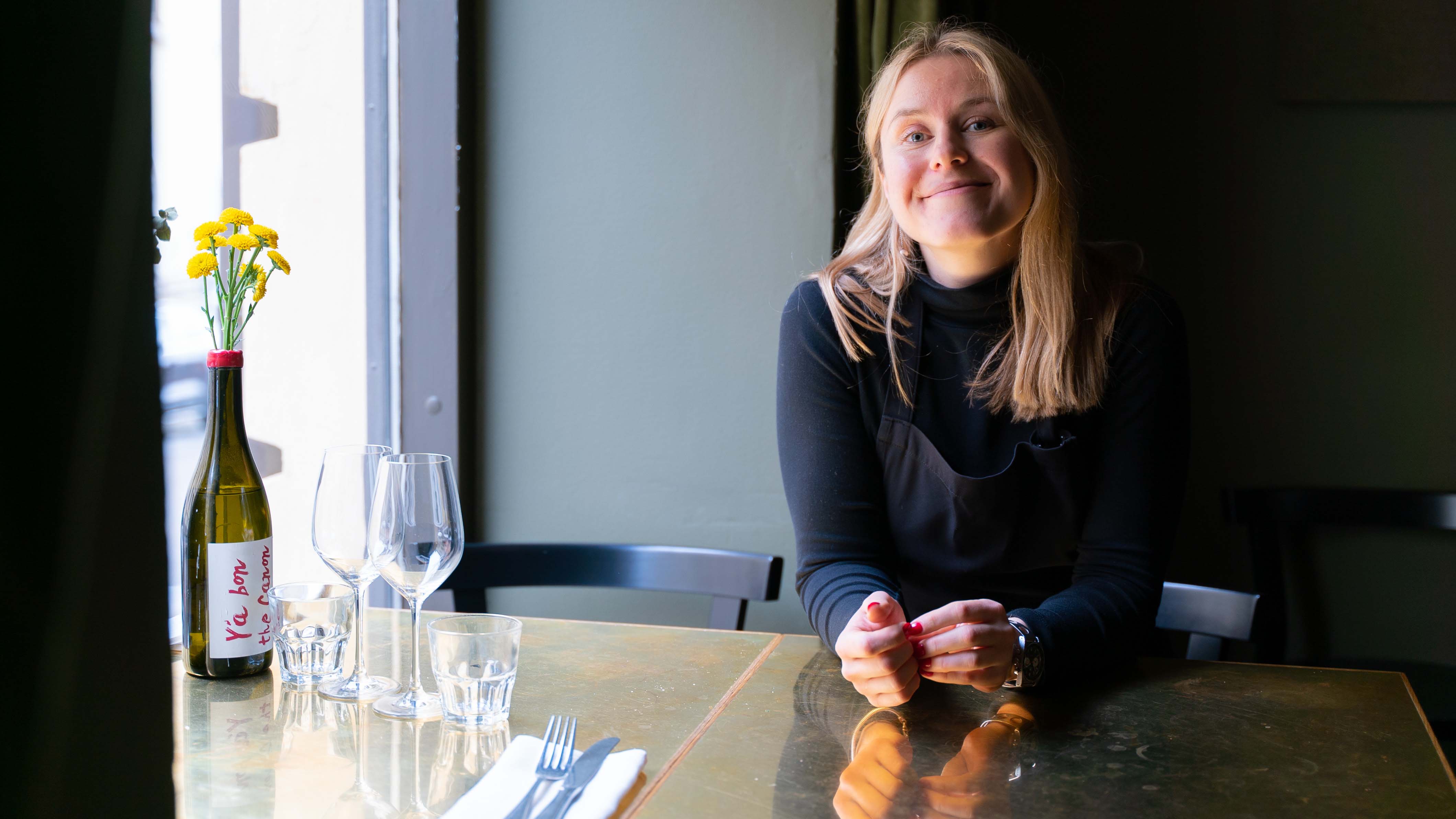 The restaurateur of Kuurna sitting behind the restaurant's table.