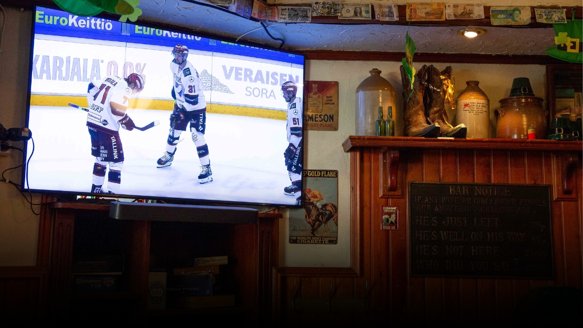 A television on the restaurant wall displaying a hockey game.