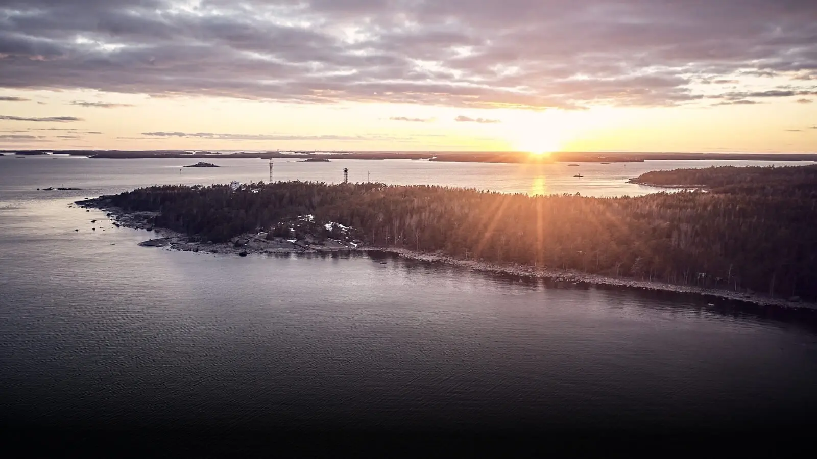 Aurinko laskemassa vesistön taakse. Keväinen tunnelma.
