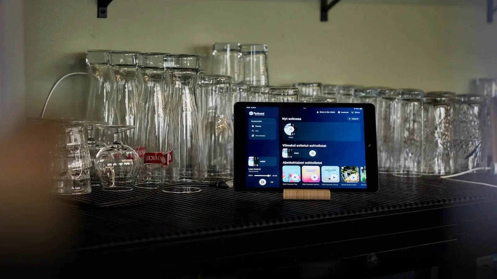Ravintolan baaritiskillä oleva tabletti, jossa päällä Feelmentin taustamusiikkisovellus.