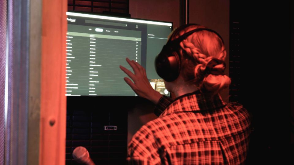 A woman selecting a song to sing in a karaoke booth.