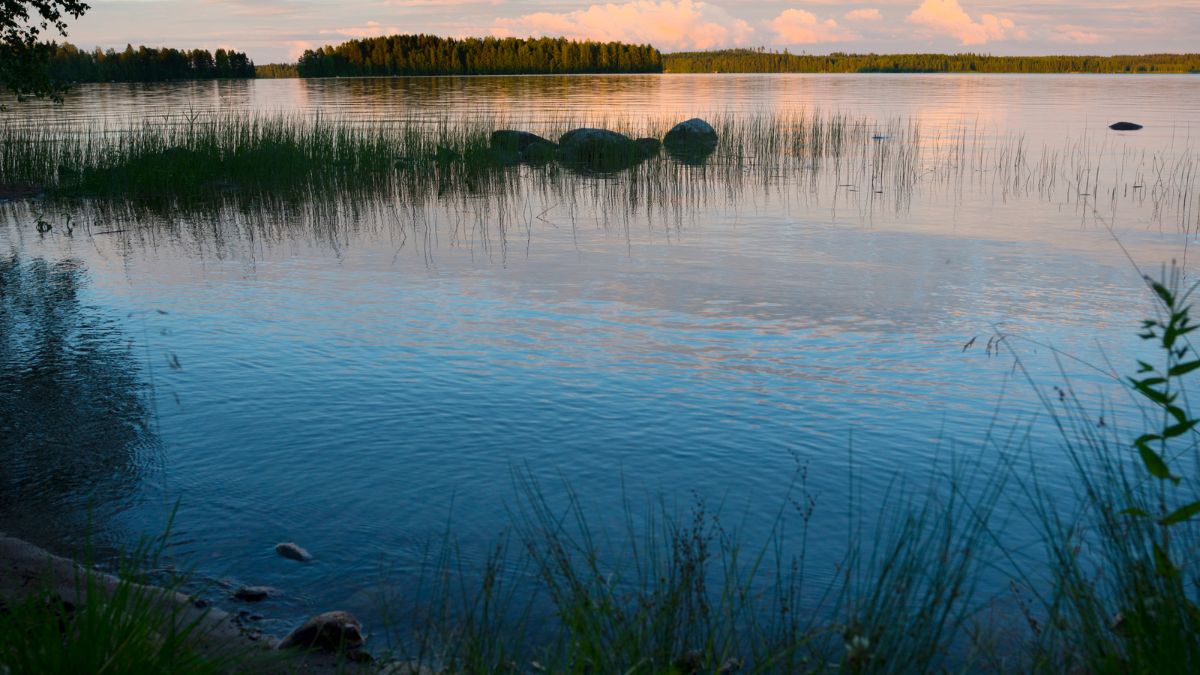 Järvimaisema, jossa sinertävää vettä ja punertava auringonlasku.