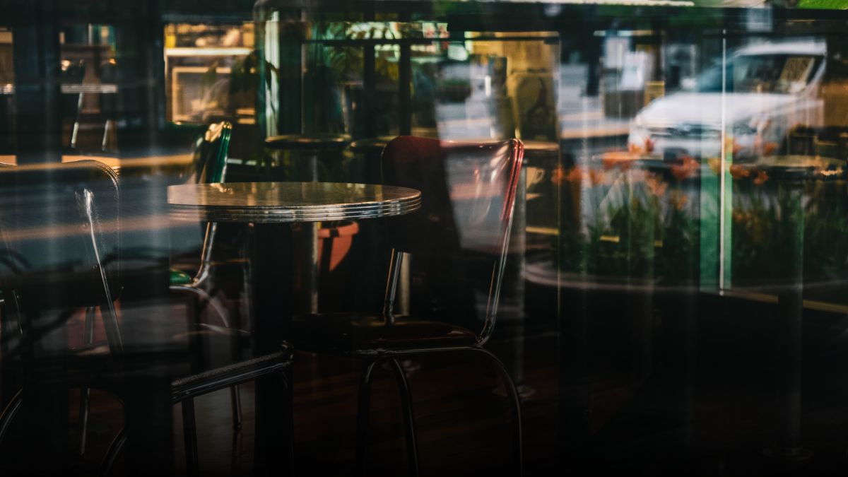 Restaurant tables and chairs photographed from outside the window.