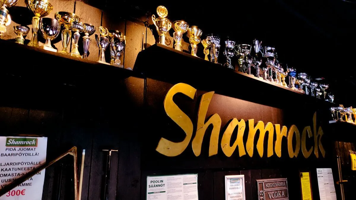 A wall in the restaurant adorned with shelves full of trophies. In the center, the Shamrock logo is prominently displayed.