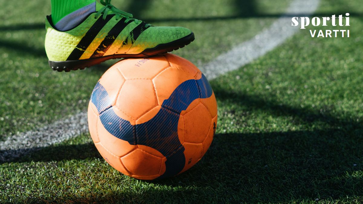 A footballer holding a ball under their foot.